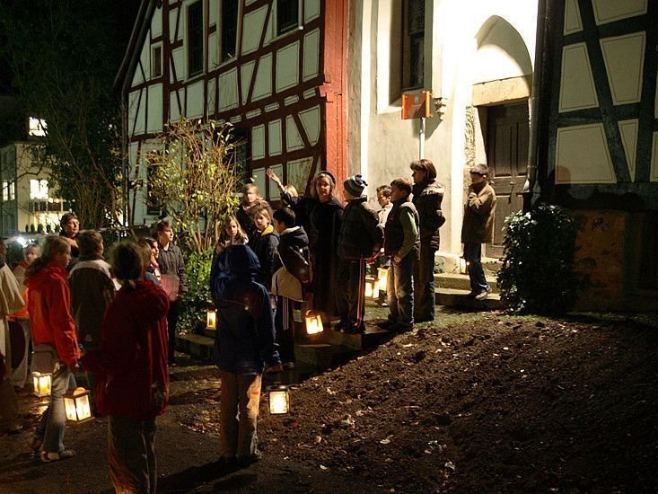 Menschen versammeln sich bei Nacht vor einem historischen Gebäude mit Laternen