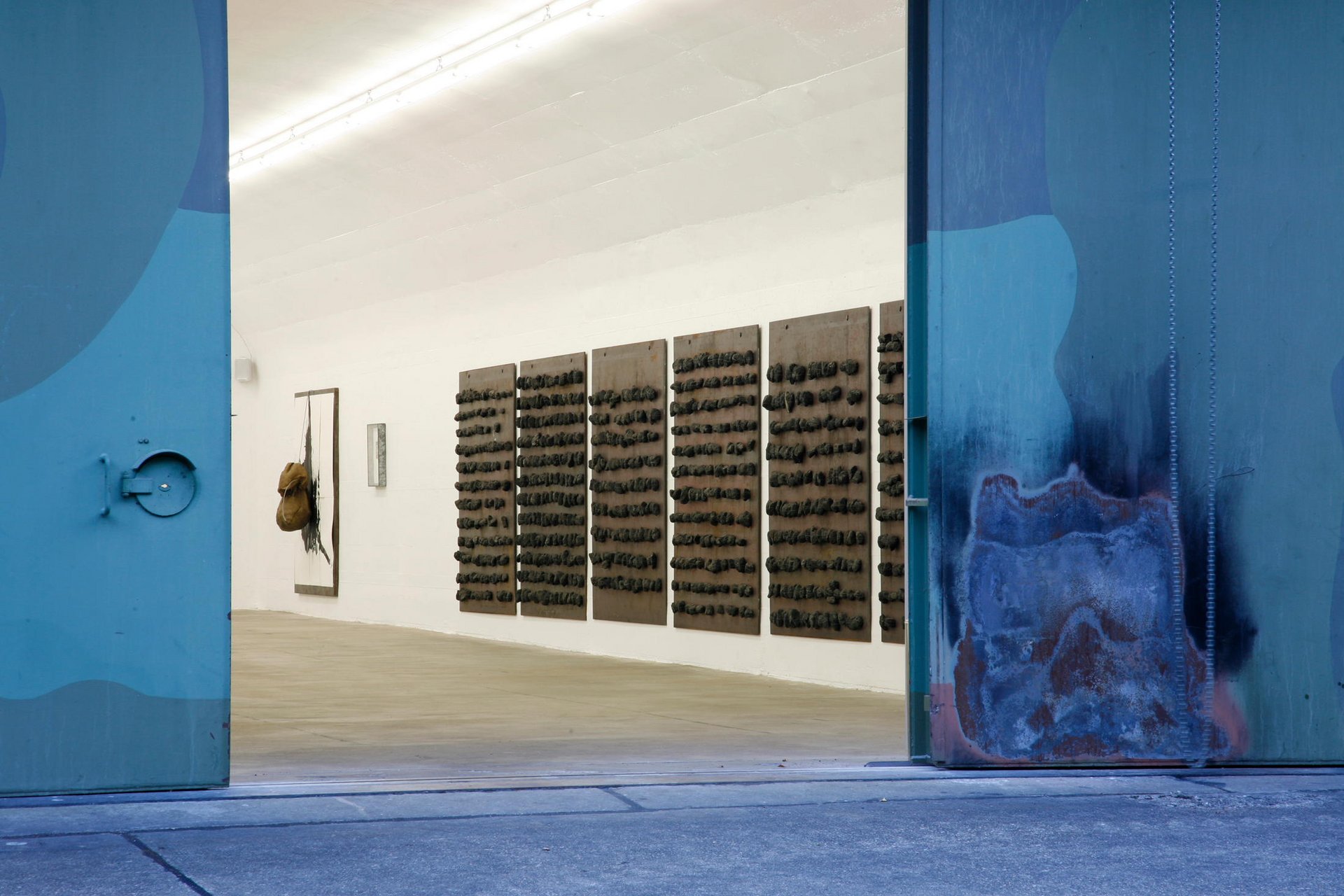 Türen öffnen sich zu einer modernen Kunstausstellung mit dunklen Kunstwerken