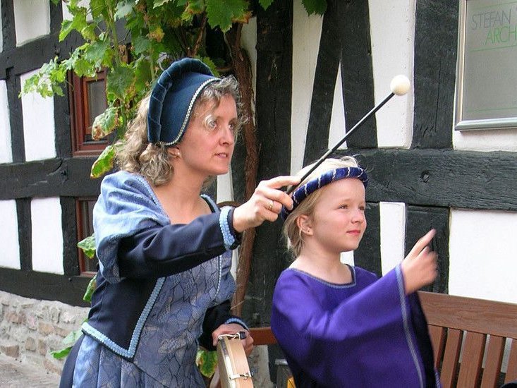 Frauen im historischen Gewand zeigen auf ein Objekt in der Nähe