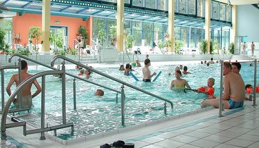 Belebtes Schwimmbad mit Kindern und Erwachsenen im Wasser