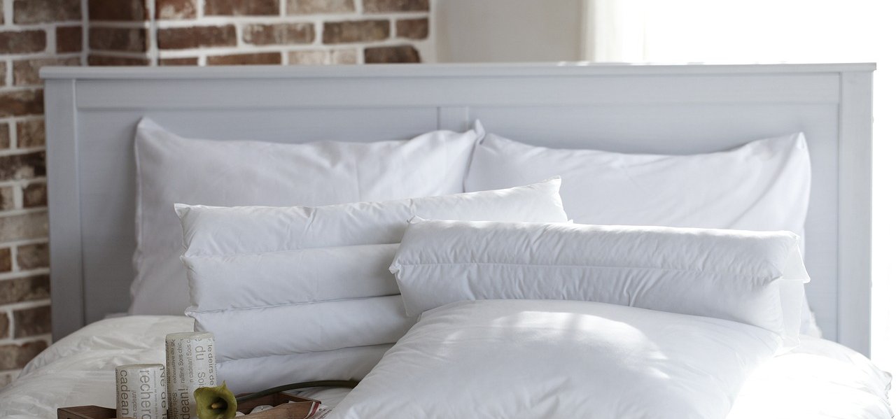 Gemütliches Bett mit weißen Kissen und einem Tablett auf der Bettdecke