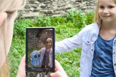 Person mit Smartphone entdeckt das virtuelle Burggespenst der Sporkenburg per Augmented Reality.