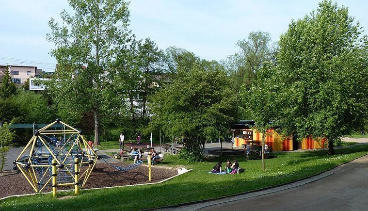 Grüne Landschaft mit Spielplatz und Gruppen von Jugendlichen auf dem Rasen