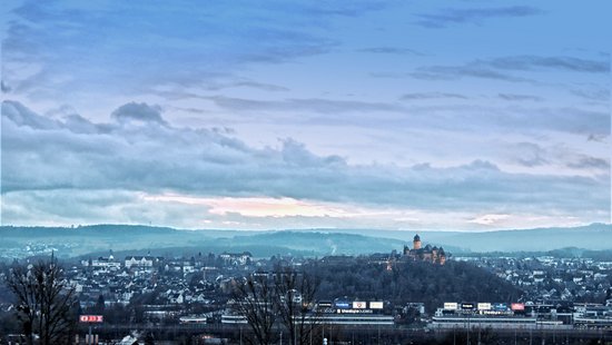 Blick auf eine Stadt mit Hügeln und Wolken am Himmel